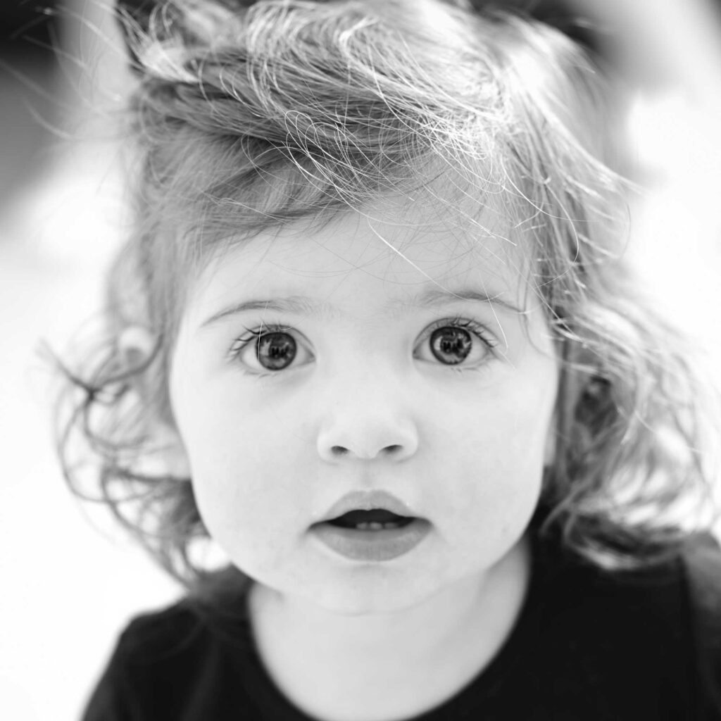 Portrait en noir et blanc d'une jeune fille au regard profond et captivant qui incarne la présence, la confiance et la beauté intemporelle.