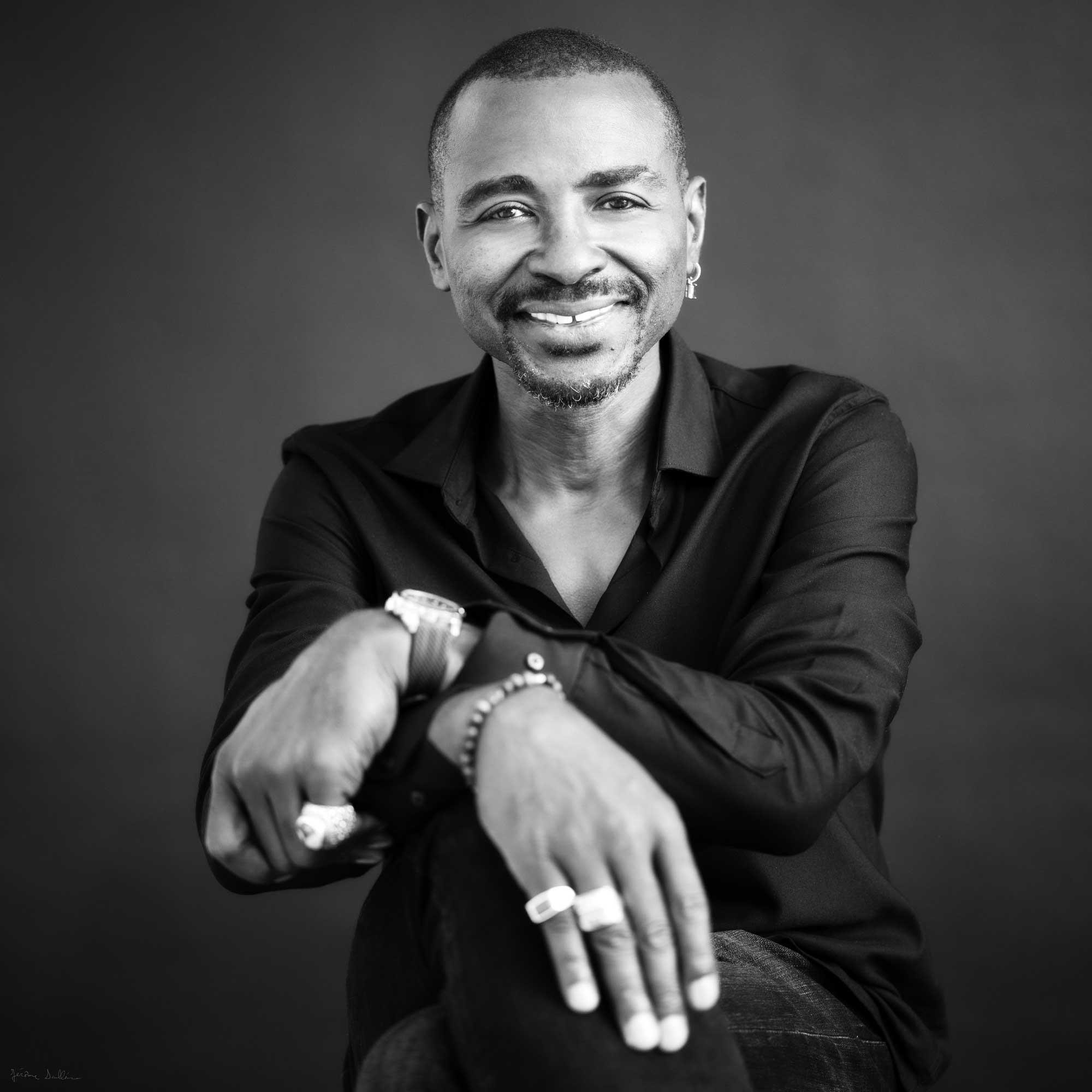 Portrait de studio en noir et blanc d'un homme souriant, capturé avec une approche fine art.