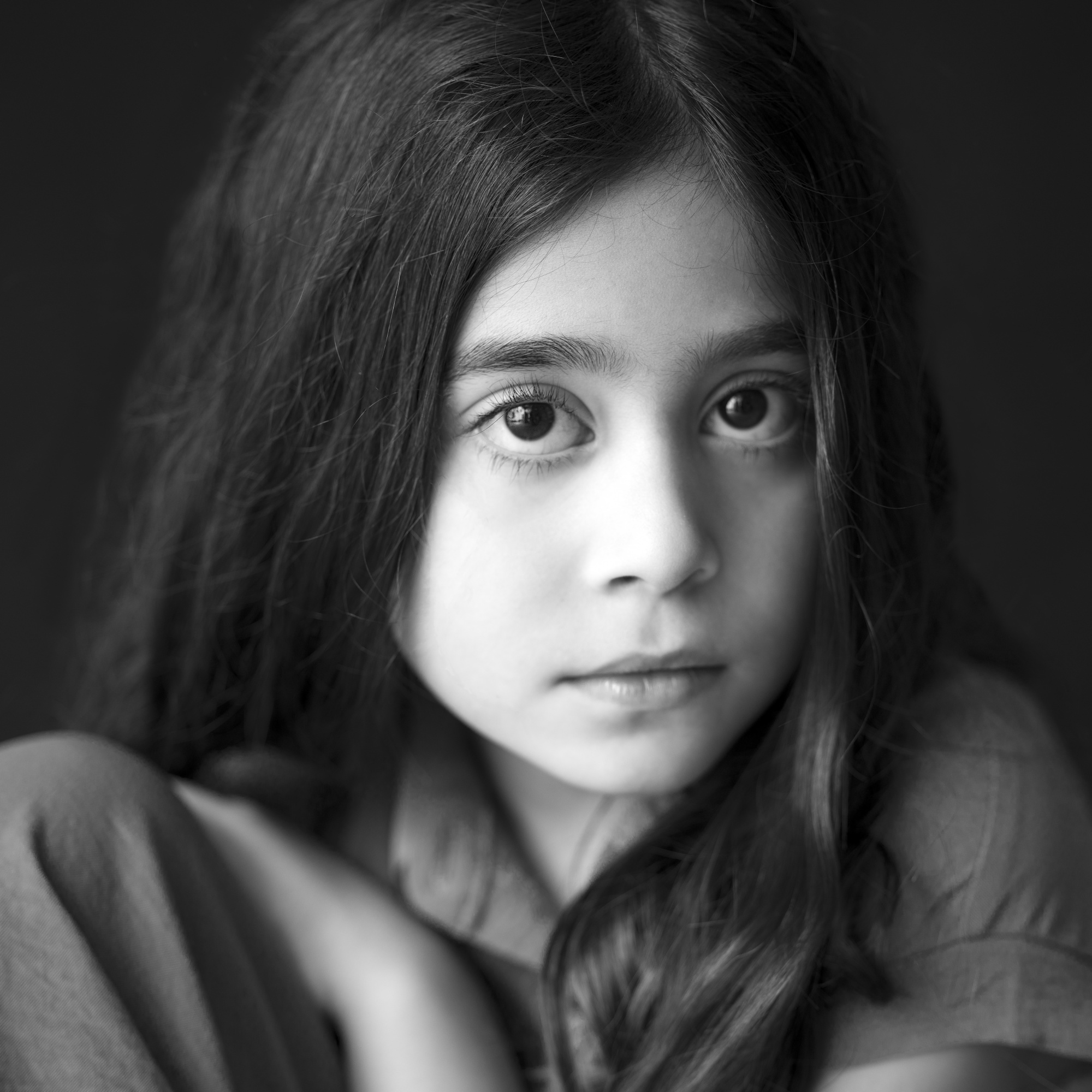 Portrait en noir et blanc d'une jeune fille aux cheveux longs et raides, regardant doucement l'appareil photo, par Jerome Art Photography.