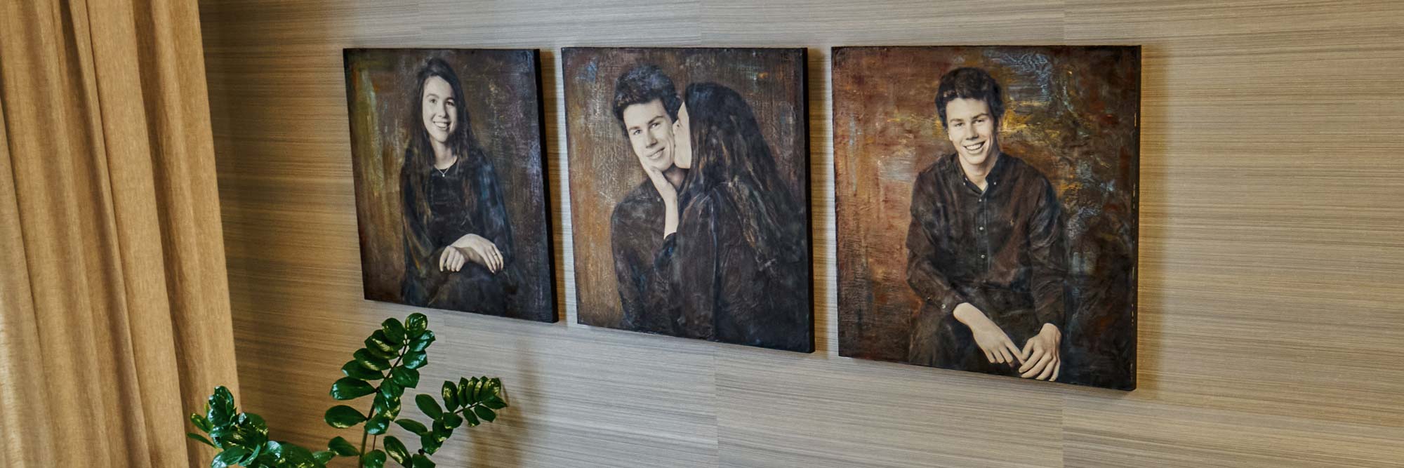 Mixed-media portrait triptych of a teenage sister and brother hanging on a warm neutral wall in a contemporary living room, with a green plant in the foreground.
