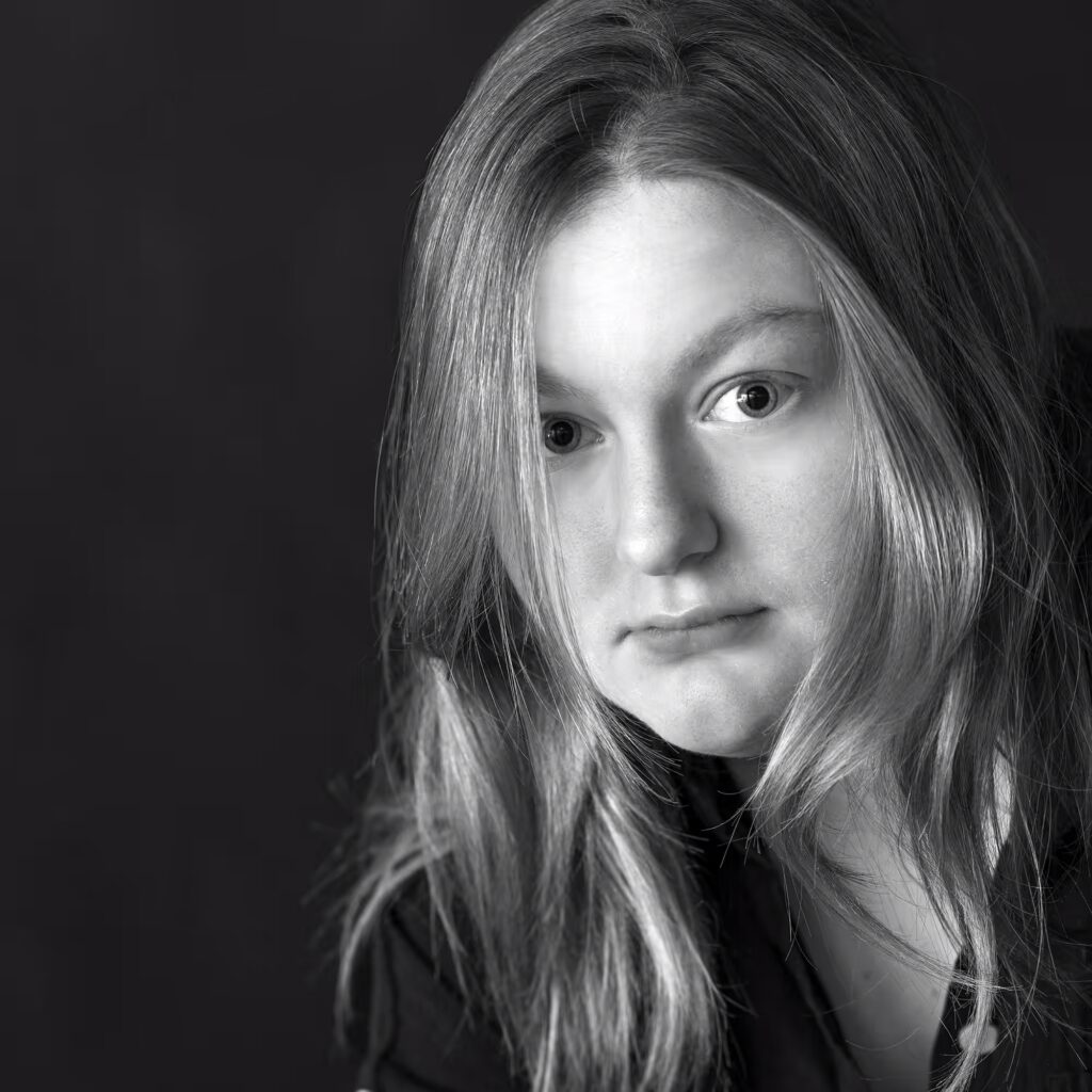 Young woman in a quiet black and white portrait, photographed with soft light and a calm, introspective expression.